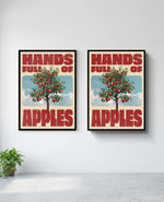 Hands Full of Apples art print in black frame, installed on wall