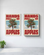 Hands Full of Apples art print in white frame, installed on wall